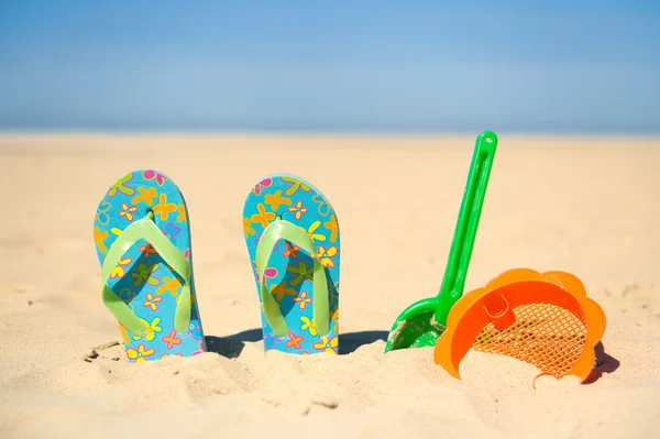 Juguetes y chanclas en la playa — Foto de Stock