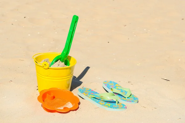 Speelgoed en flip-flops op het strand — Stockfoto