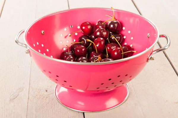Cherries in pink colander — Stock Photo, Image
