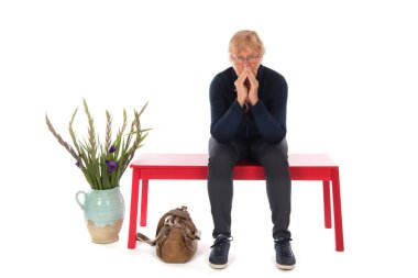 Üzgün yaşlı kadın beyaz arka planda yalnız bekliyor.