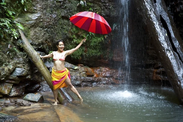 Mädchen mit Regenschirm am Wasserfall im Borneo-Regenwald — Stockfoto