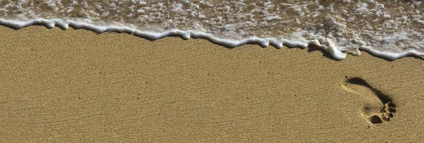 Voetafdruk op strand met golven — Stockfoto