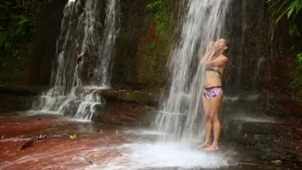 Сексуальна дівчина з бікіні приймає душ у водоспаді — стокове відео