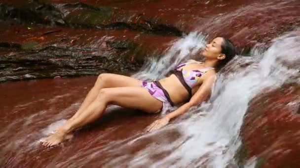 Sexy dziewczyna w bikini, leżącej w wodospad rzeki — Wideo stockowe