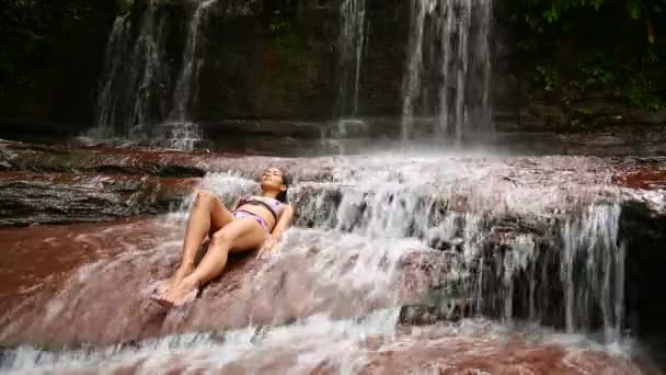 sexy Mädchen mit Bikini im Wasserfall liegend