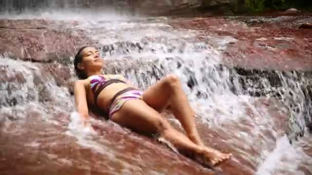 Sexy girl with bikini lying down in waterfall river — Stock Video