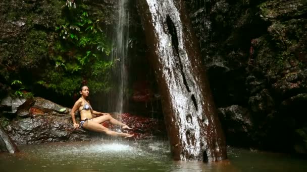 Сексуальна дівчина з бікіні лежить у водоспаді — стокове відео