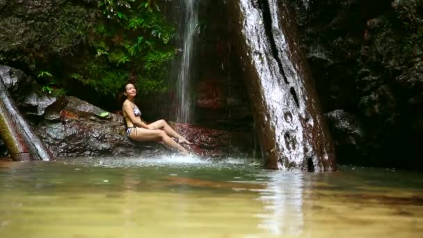 Сексуальна дівчина з бікіні лежить у водоспаді — стокове відео