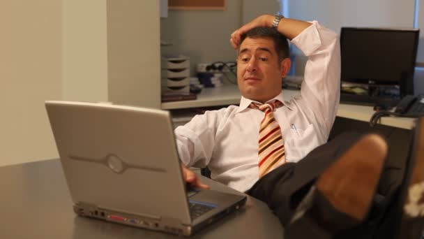 Hombre de negocios relajado usando el ordenador portátil en la oficina — Vídeos de Stock
