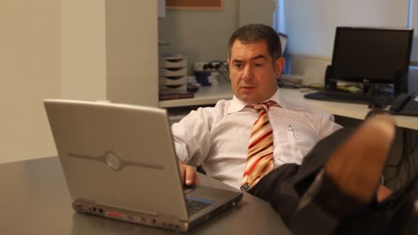 Relaxed businessman using laptop in office — Stock Video