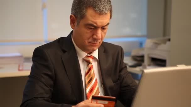Empresário com cartão de crédito, usando laptop no escritório — Vídeo de Stock
