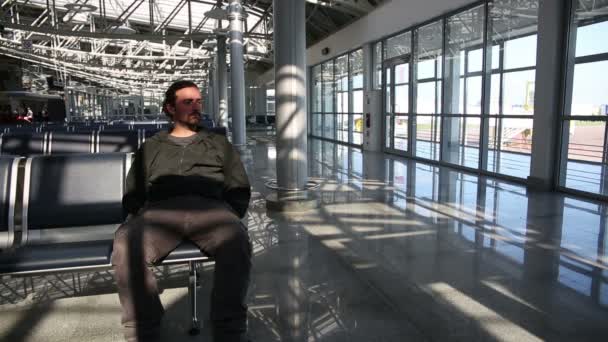 Mladý muž čeká jeho letu v letištní hale — Stock video