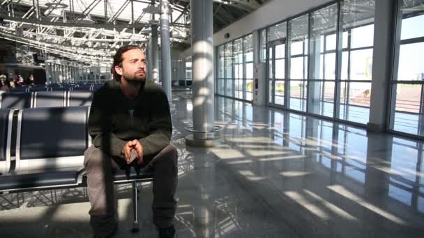 Młody człowiek czeka jego lotu w poczekalni — Wideo stockowe