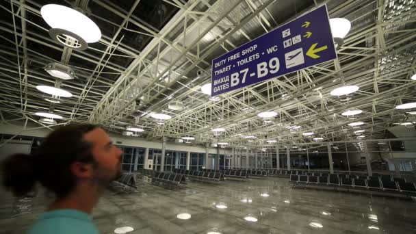 Joven mirando la dirección de la cartelera en el aeropuerto — Vídeos de Stock