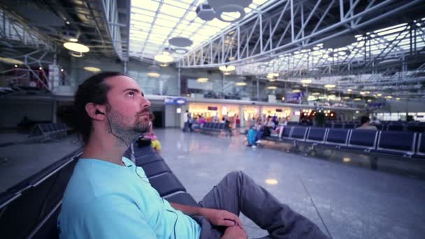 Mladý muž čeká jeho letu v letištní hale — Stock video