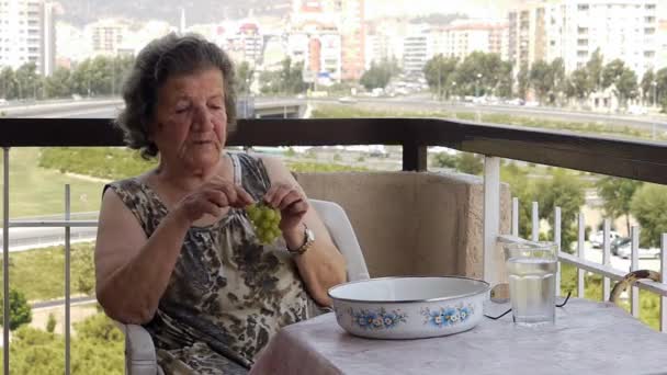 Old retired woman eating grapes on balcony — Stock Video