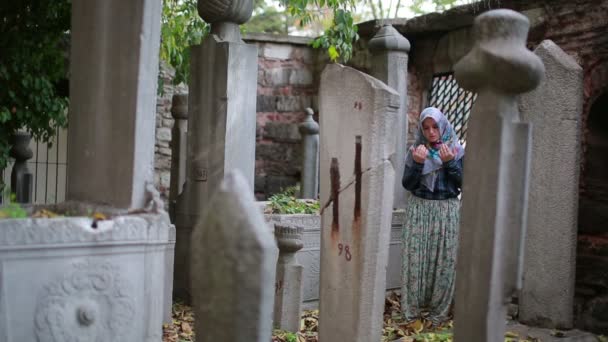 Muslim girl praying in small graveyard — Stock Video