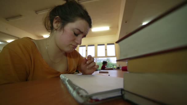 Distressed young girl working in library reading room — Stock Video