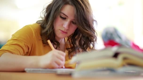 Feliz joven estudiante leyendo libro en la biblioteca — Vídeos de Stock