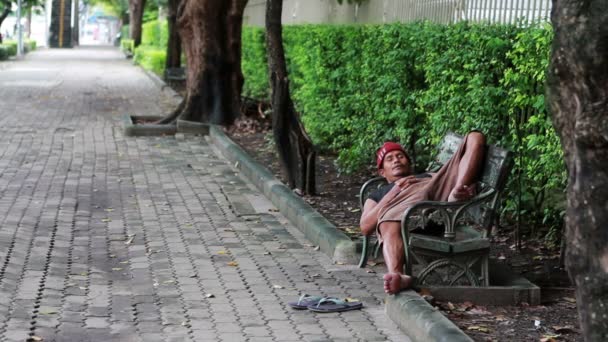 Бездомный спит на скамейке — стоковое видео
