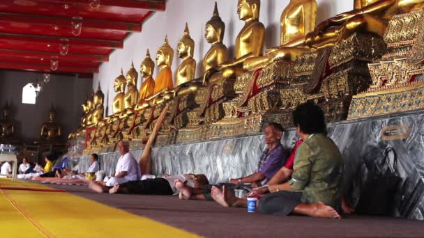 Siede sotto statue di buddha dorati — Video Stock