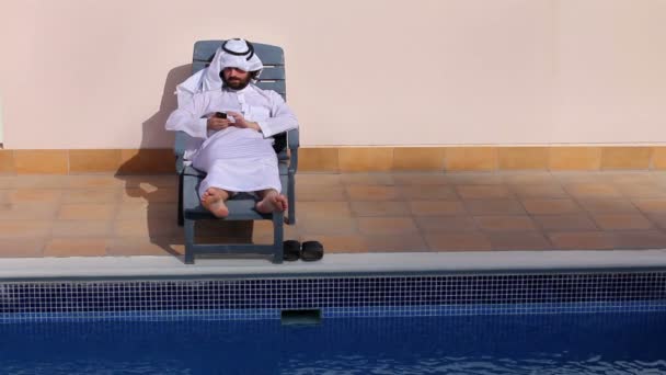 Saoedi-Arabische man met zijn telefoon bij zwembad — Stockvideo