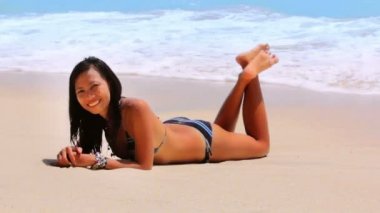 Seksi Asyalı kız egzotik plajda güneşlenirken ve bronzlaşma