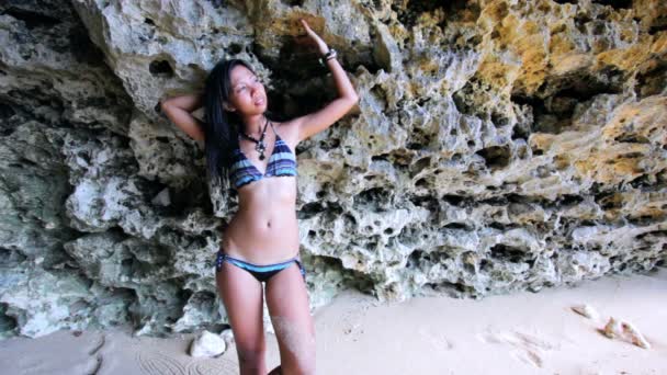 Сексуальная азиатская девушка на экзотическом пляже против рока — стоковое видео