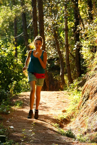 Sexig tjej kör längs smala stigen i skogen Stockbild