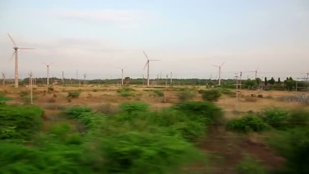Поезд проезжает мимо ветряной электростанции — стоковое видео