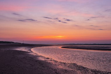 Almanya 'nın Amrum adasında gün doğumuyla çamurlu bir düzlük..