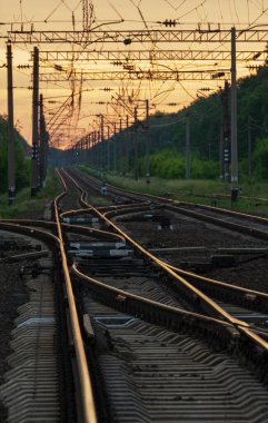 Demiryolu kavşağı ve turuncu gün batımı ışığında gidiş çizgileri