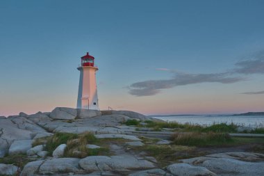 Photograph of the iconic Peggy's Cove lighthouse taken at sunrise on a beautiful summer morning.