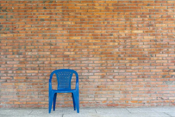 Single Blue Plastic Chair Front Clay Brick Wall Stock Photo