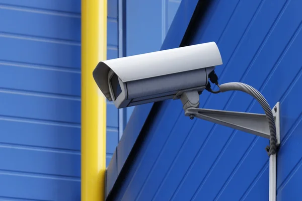 Surveillance camera next to yellow pipe — Stock Photo, Image