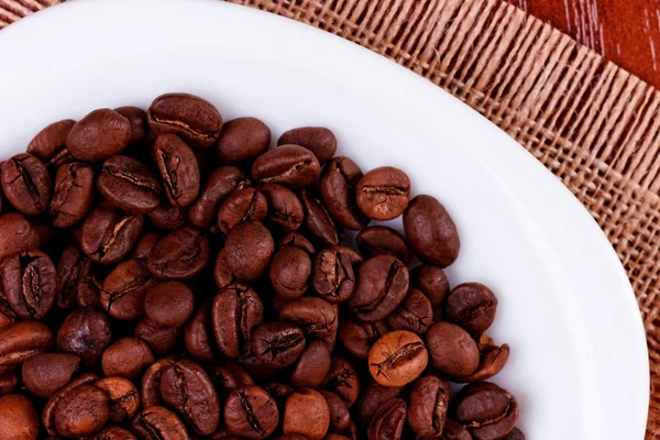 Un plato con granos de café oscuro —  Fotos de Stock