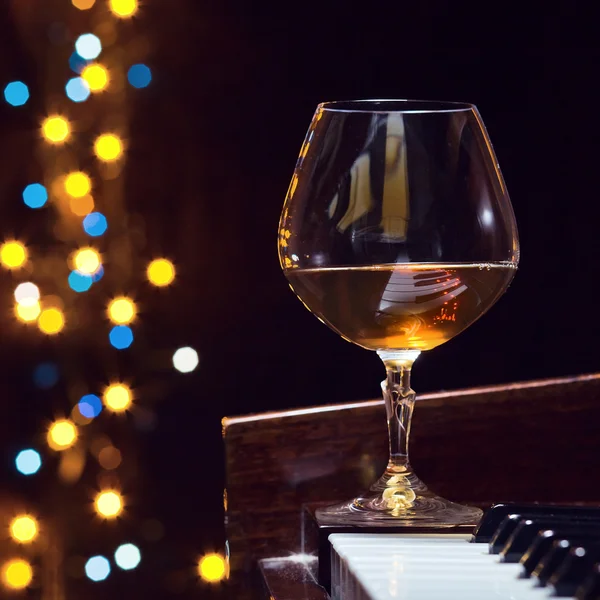 Snifter with brandy on a piano — Stock Photo, Image