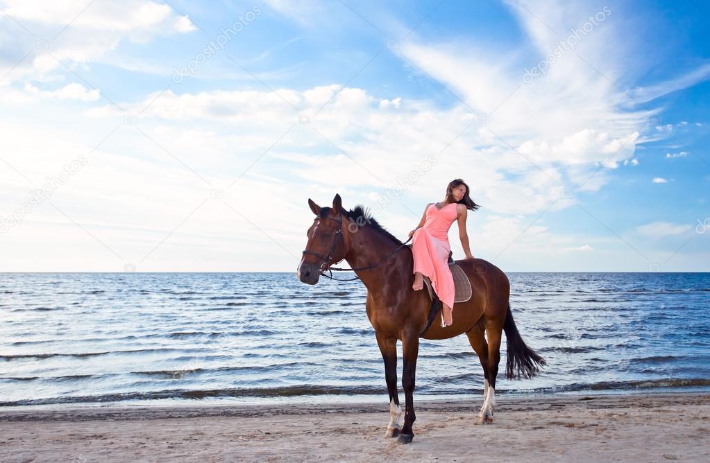 girl in pink dress with horse on seacoast