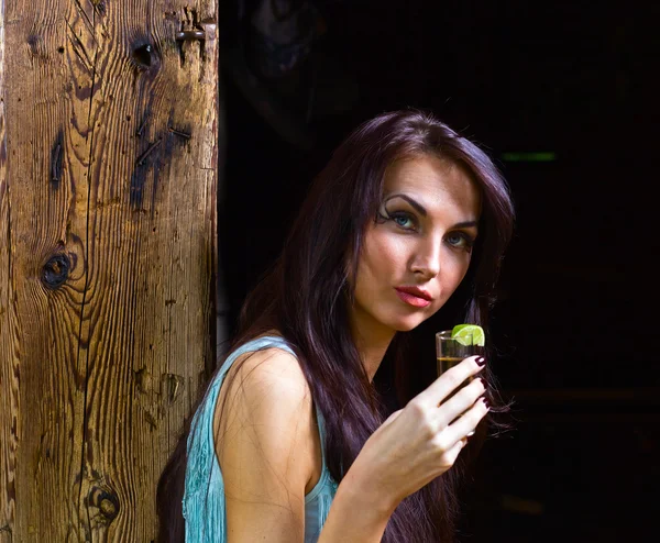 Jonge schoonheid met tequila in de oude houten huis — Stockfoto