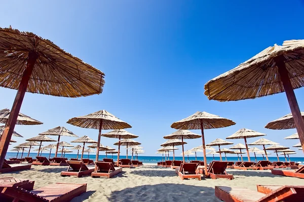 Solstolar och parasoller på stranden — Stockfoto