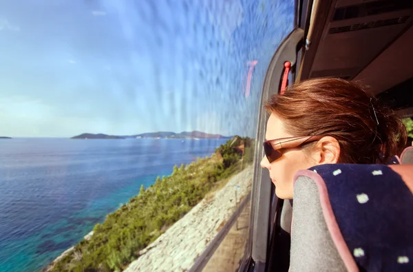 Mujer en el autobús mira por la ventana a un paisaje marino —  Fotos de Stock