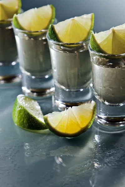 Tequila y lima sobre mesa de vidrio —  Fotos de Stock