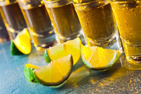 Tequila y lima sobre mesa de vidrio — Foto de Stock