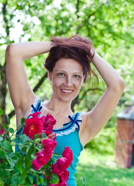 Mujer de mediana edad cerca de un arbusto de rosas —  Fotos de Stock