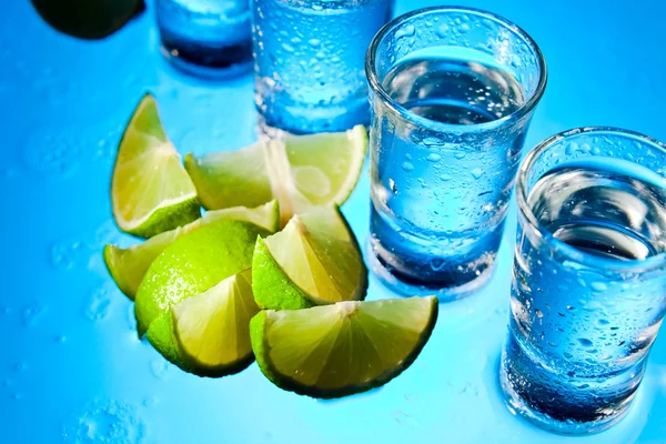 Tequila e lime su tavolo di vetro — Foto Stock