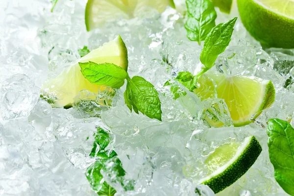 Lime pieces and leaves of mint with ice — Stock Photo, Image