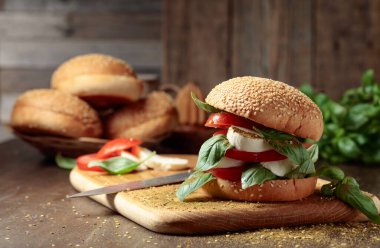 Eski ahşap bir masada mozarella, domates ve fesleğenli sandviç..