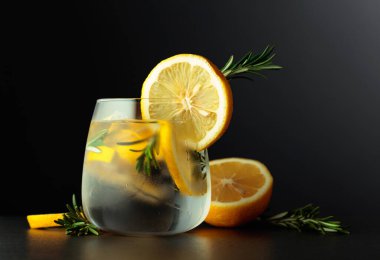 Limon dilimleri ve siyah arka planda biberiye dalıyla kokteyl cin toniği. Boşluğu kopyala.