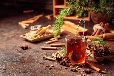 Tarçınlı, anasonlu ve kurutulmuş otlu Noel çayı. Kahverengi bir masada ardıç dallı bitki çayı. Boşluğu kopyala.