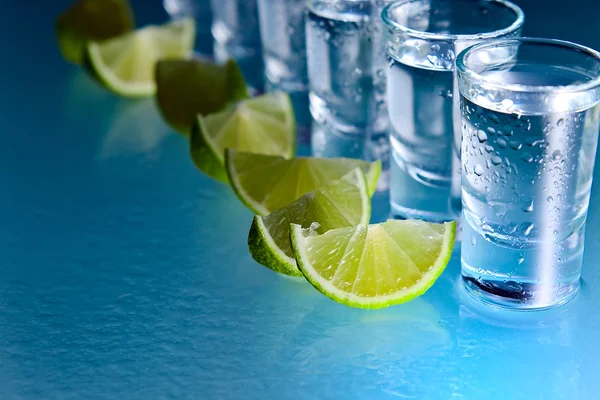 Tequila e lime su tavolo di vetro — Foto Stock